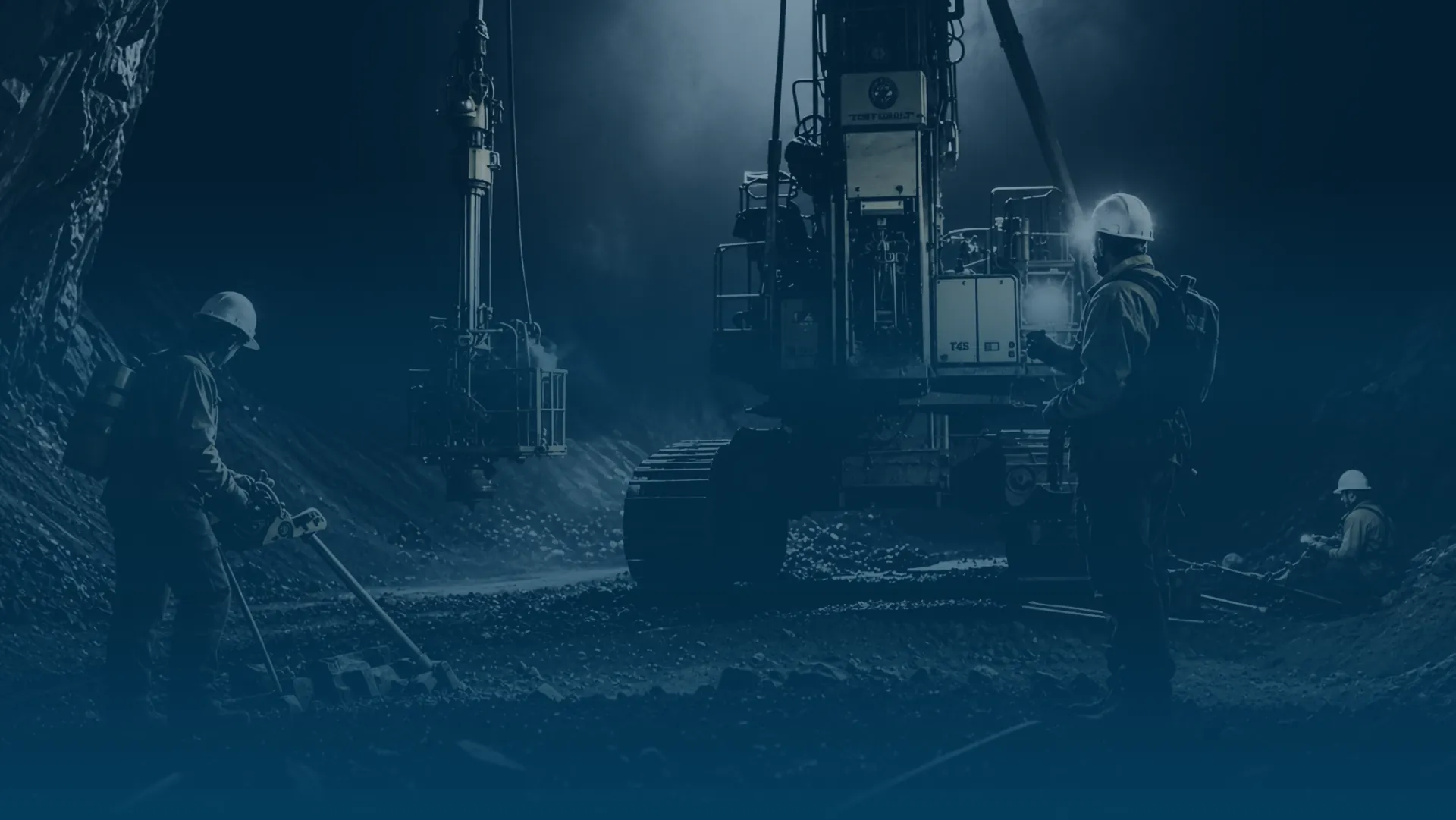 Drill crew working a rig underground, lit by machine floodlights
